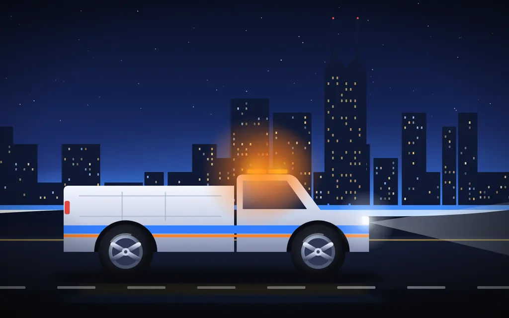 Roadside service truck with amber light bar driving at night past the Nashville skyline